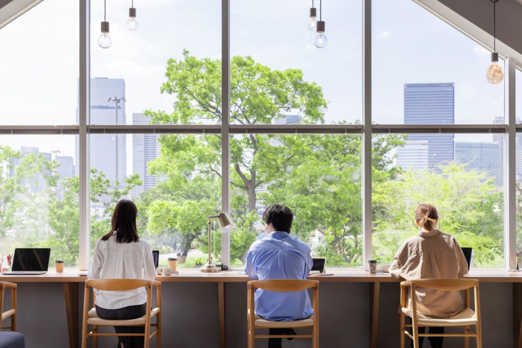 窓辺のあるオフィスで仕事する人たち