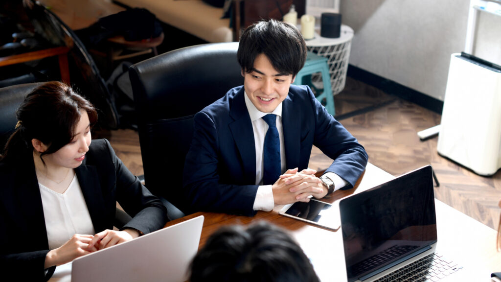 会議している4人、笑う男性